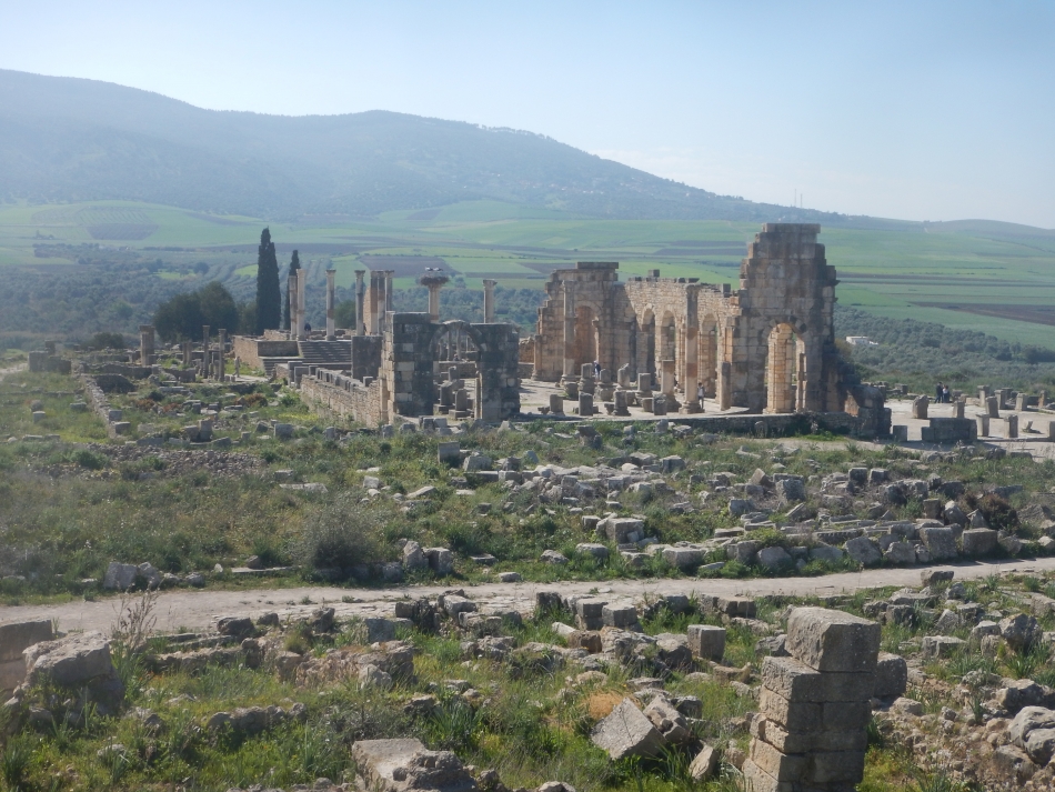 Le quartier monumental de la Basilique et du Capitole au cœur du site de Volubilis. En arrière-plan, les contreforts du massif du Zerhoun. 